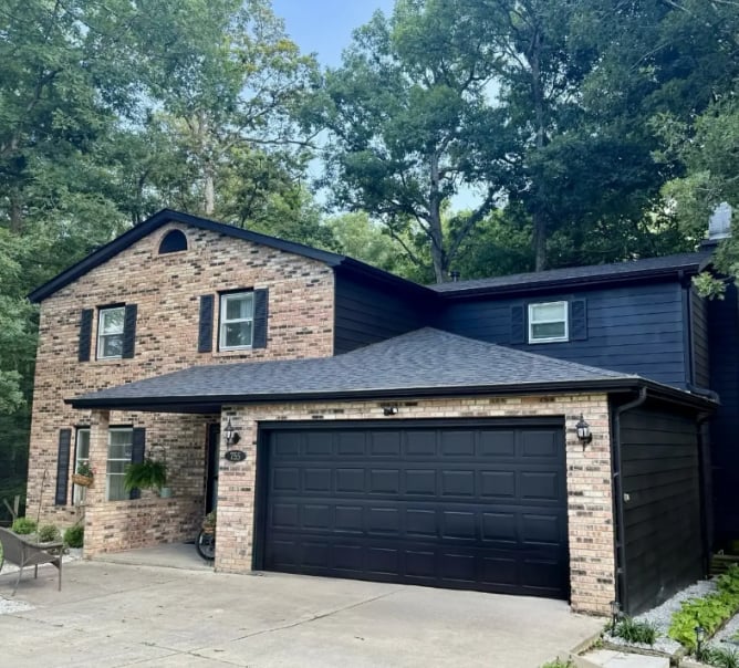 Clean Cut Painting & Handyman exterior painting project in Springfield Illinois - two-story brick home with dark navy blue siding, black shutters and black garage door