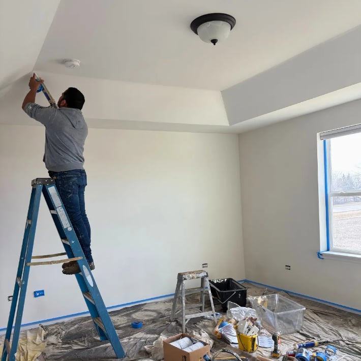 Professional painter on ladder painting interior ceiling in Decatur Illinois home