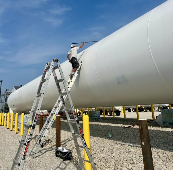 Professional painter on ladder painting large industrial tank - commercial painting contractor Decatur IL Clean Cut Painting