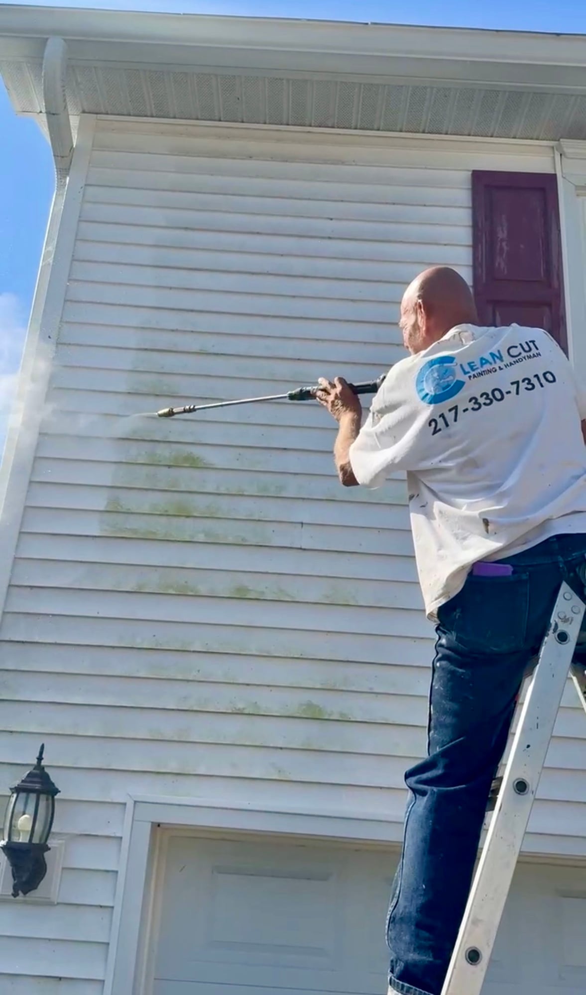Clean Cut Painting and Handyman technician power washing home siding near Decatur Illinois
